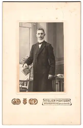 Fotografie Atelier Mentzen, Mülheim / Ruhr, Eppinghoferstr. 26, junger Mann im hoch geschlossenen Anzug mit Mantel