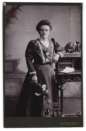 Fotografie Louis Schindhelm, Ebersbach, junge Dame im Biedermeierkleid mit Bestickung lehnt an einem Sekretär