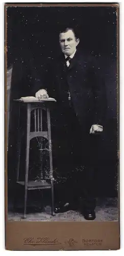 Fotografie Chr. Klünder, Nortorf / Holstein, betagter Herr im Anzug blättert in einem Buch