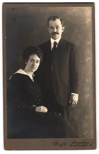 Fotografie Rost, Dresden, Wettinerstr. 15, Paar im schwarzen Kleid und Anzug mit Moustache