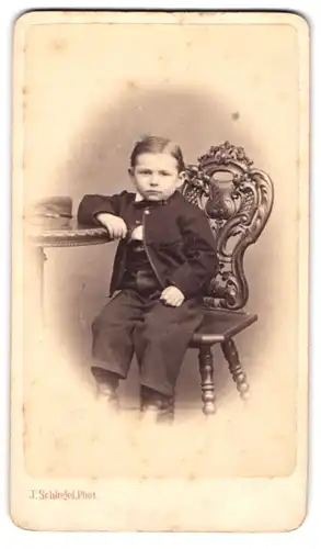 Fotografie J. Schlegel, Zittau, kleiner sächsischer Knabe im Anzug sitzt auf einem Stuhl am Tisch