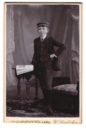 Fotografie Wilh. Gerlich, Neu-Ruppin, Paradeplatz, junger Studentim Anzug mit Schirmmütze posiert im Atelier