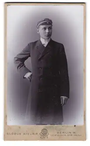 Fotografie Globus Atelier, Berlin, Leipzigerstr. 132 /135, Student im Anzug mit Mantel und Schirmmütze