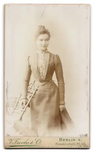 Fotografie J. Fuchs & Co., Berlin, Friedrichstr. 108, Frau mit Plattenkamera betrachtet eine Fotografie mit Lupe, Putto