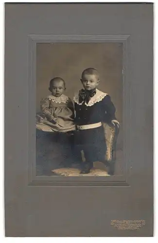 Fotografie Adolph Richter, Leipzig-Lindenau, Merseburger Str. 61, Zwei Kleinkinder auf Stuhl mit Spitzenkragen