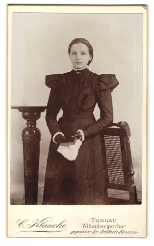 Fotografie C. Klaucke, Torgau, Portrait junges Mädchen im schwarzen Kleid mit Bibel und Lederhandschuhen, Kommunion