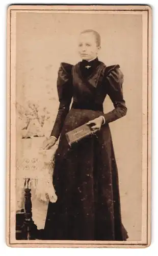 Fotografie unbekannter Fotograf und Ort, junges Mädchen im schicken schwarzen Kleid mit Bibel in der Hand, Kommunion