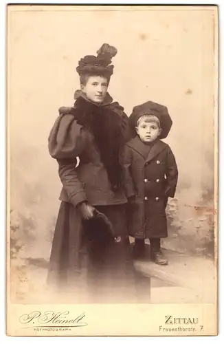 Fotografie P. Heinelt, Zittau, Frauenthorstr. 7, Mutter im Winterkleid mit Muff und Sohn im Wintermantel, Mutterglück