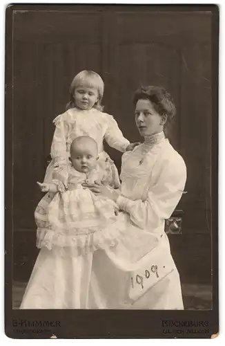 Fotografie G. Klimmer, Bückeburg, junge Mutter im weissen Kleid mit ihren beiden Töchtern in weissen Kleidern, Mutterglück