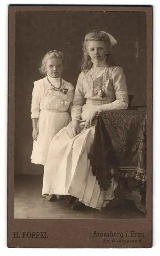 Fotografie H. Föppel, Annaberg i. Erzg., junge Frau im weissen Kleid mit ihrer blonden Tochter, Mutterglück