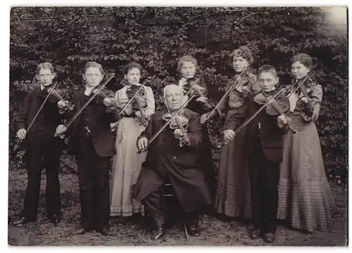 Fotografie unbekannter Fotograf und Ort, Geigenlehrer mit seinen sieben Schüler / innen im Garten