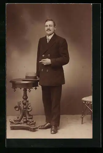 Foto-AK Sympathischer herr mit Zigarette in Studiokulisse