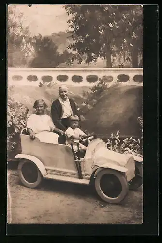 Foto-AK Dame mit Kindern in Holzauto vor Landschaftskulisse