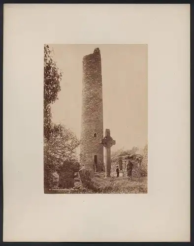 Fotografie W. L., Ansicht Mainistir Bhuite / Irland, Turm und Hochkreuz auf einem verfallenen Friedhof