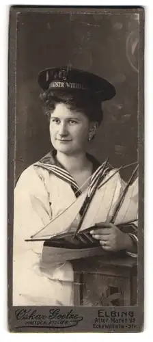 Fotografie Oskar Goetze, Elbing, junge Frau als Matrosin mit Mützenband SMS Kaiser Wilhelm mit Modellschiff