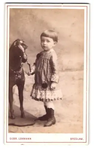 Fotografie Gebr. Lehmann, Breslau, Portrait kleines Mädchen im Kleidchen mit Schaukelpferd