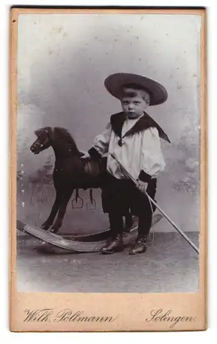 Fotografie Wilh. Pollmann, Solingen, Portrait niedlicher Knabe mit Sommerhut und Schaukelpferd im Atelier