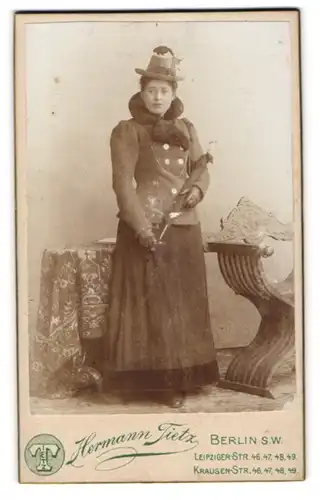 Fotografie Hermann Tietz, Berlin, Dame im Winterkleid mit Pelzkragen und Federhut, Schirm