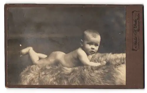 Fotografie H. Deike, Hannover-Linden, Deisterstr. 7, Portrait nacktes Baby liegt auf einem Fell