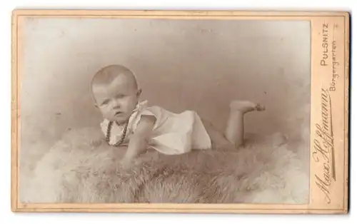 Fotografie Max Hoffmann, Pulsnitz, Bürgergarten, Portrait süsses Baby im Hemdchen auf einem Fell liegend