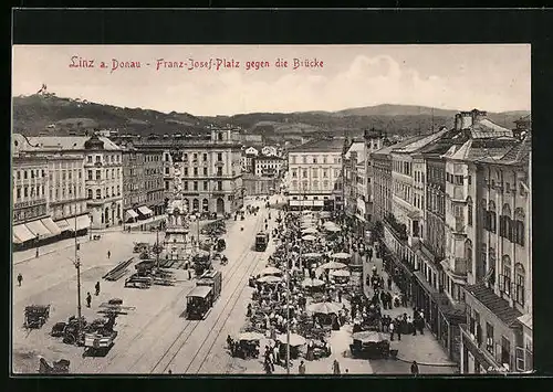 AK Linz a. Donau, Franz Josef-Platz mit Geschäften und Denkmal gegen die Brücke, Strassenbahn