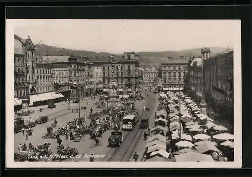 AK Linz a. d. D., Platz d. 12. November mit Geschäften und Denkmal, Strassenbahn
