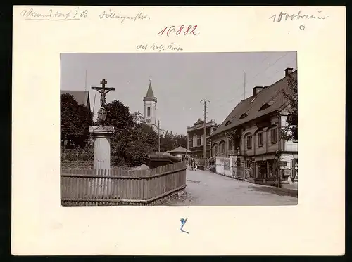 Fotografie Brück & Sohn Meissen, Ansicht Warnsdorf i. B., Strassenansicht mit Ladengeschäft, Flurkreuz und Kirchturm