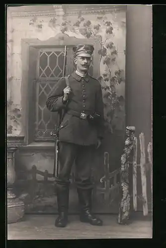 Foto-AK Soldat in Feldgrau mit Schirmmütze und seinem Karabiner um die Schulter