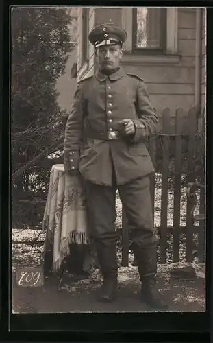 Foto-AK Junger Soldat in Feldgrau mit Schirmmütze und Zigarre in der Hand