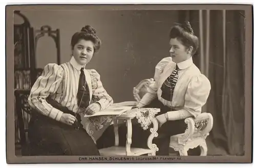 Fotografie Chr. Hansen, Schleswig, Lollfuss 98 b, Zwei junge Damen in modischen Blusen mit Zeitung am Tisch