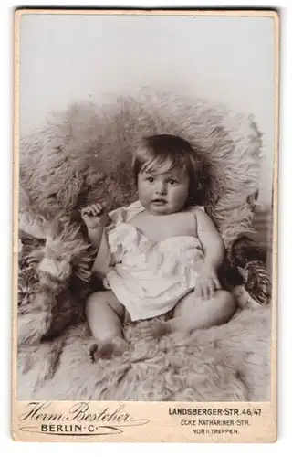 Fotografie Hermann Besteher, Berlin-C, Landsbergerstr. 46-47 Ecke Katharinenstr., Süsses Kleinkind im Hemd sitzt auf Fell
