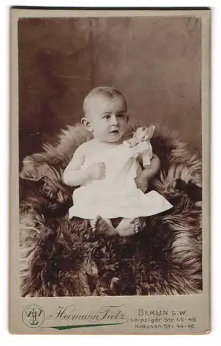 Fotografie Hermann Tietz, Berlin-SW, Leipziger-Str. 46-49, Süsses Kleinkind im Hemd sitzt auf Fell