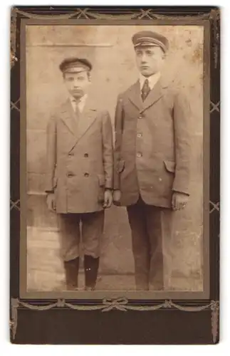 Fotografie unbekannter Fotograf und Ort, Zwei junge Männer im Anzug mit Schirmmütze