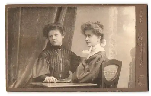 Fotografie J. Fuchs, Berlin-C., Königstr. 52, Zwei junge Damen in Kleidern mit Zeitung am Tisch
