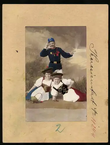 Fotografie Brück & Sohn Meissen, Ansicht Theresienstadt, K.u.K. Soldat in Uniform mit Frauen in Tracht, Hand Koloriert
