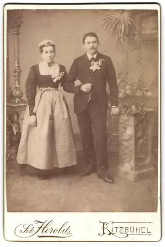 Fotografie Seb. Herold, Kitzbühel, Brautpaar in hochwertiger Festtagskleidung mit Blumengestecken