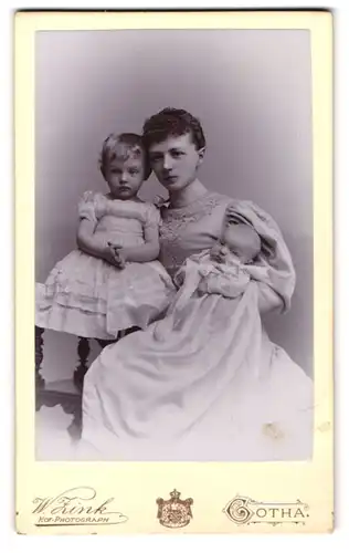 Fotografie W. Zink, Gotha, Auguststrasse 7, Heranwachsende Mutter im edlen Kleid mit ihren zwei Kleinkindern im Arm