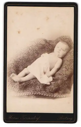 Fotografie Herrm. Zernsdorf, Belzig, Halbnacktes Kleinkind im Hemd liegt auf einer Decke