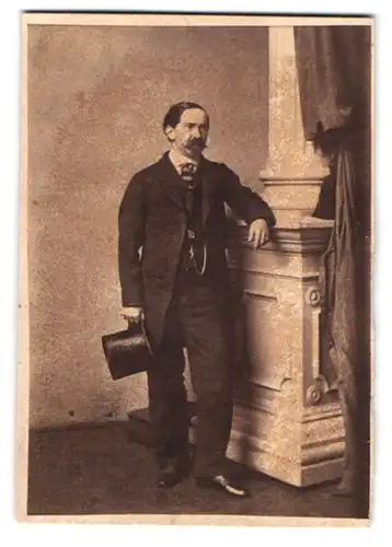 Fotografie W. Rupp, Prag, Gestandener Herr mit Spitzbart im modischen Massschneideranzug und Zylinder in der Hand