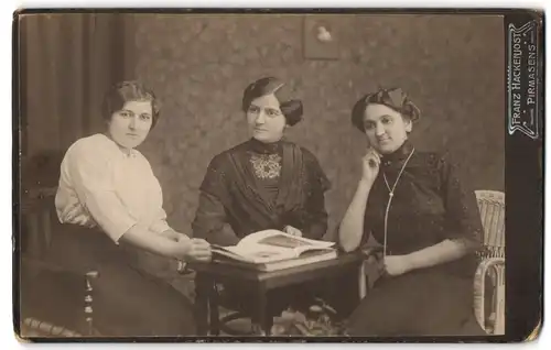 Fotografie Franz Hackenjost, Pirmasens, Drei hübsch gekleidete Damen mit Zeitung am Tisch