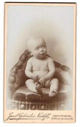 Fotografie Jacob Gebrüder Nachfl., Charlottenburg, Wilmersdorfer Strasse 56, Nacktes Baby, auf einem Sessel sitzend