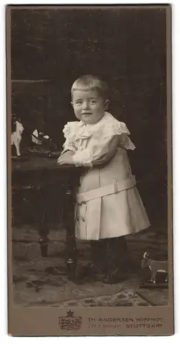 Fotografie Th. Andersen, Stuttgart, Kleines Kind in hübscher Kleidung mit Holzspielzeug