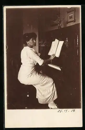 Foto-AK Gut betuchte Frau im weissen Kleid eine Seite ihres Notenheftes am Klavier umblätternd