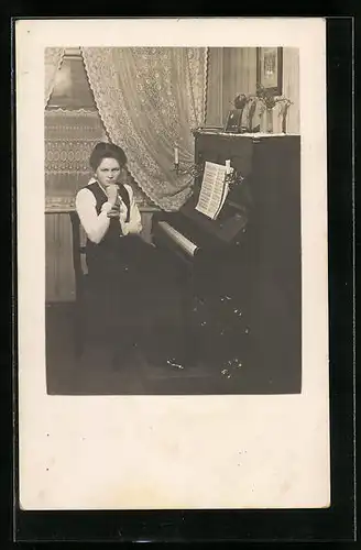 Foto-AK Heranwachsendes Mädchen mit ernster Miene am Klavier sitzend