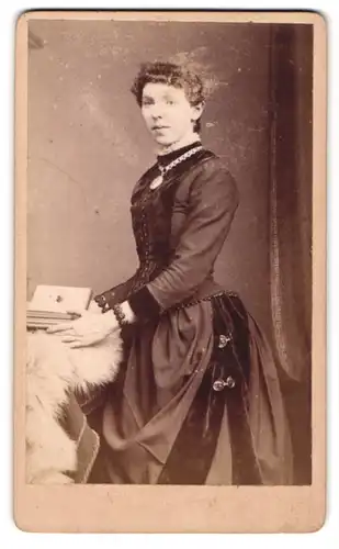 Fotografie A. Jennings & Co., Blackburn, 41, Victoria Street, Festlich gekleidete Dame mit Amulett und Album