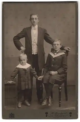 Fotografie H. Reinhard, Neustadt a. H., Jüngling im Gehrock mit zwei Knaben in festlicher Kleidung