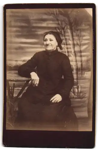 Fotografie unbekannter Fotograf und Ort, Vergnügte ältere Frau mit Kopftuch im schwarzen Kleid