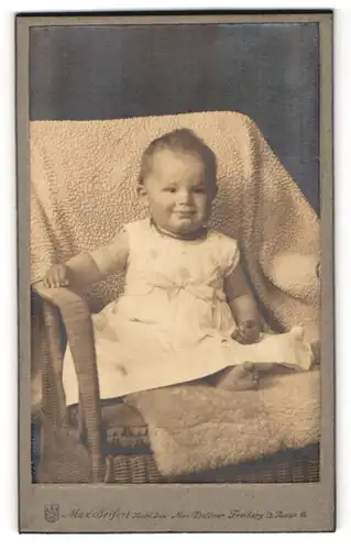Fotografie Max Seifert, Freiberg i. S., Post-Strasse 11, Lächelndes Kleinkind auf einem Sesssel