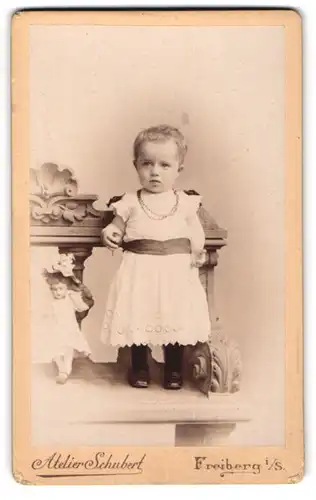 Fotografie Atelier Schubert, Freiberg i. S., Fischerstrasse 29, Kleines Kind mit kurzen Haaren im Spitzenkleidchen
