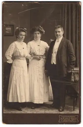 Fotografie W. Zink & Sohn, Gotha, Auguststr. 7, Junger Herr im Anzug mit zwei jungen Damen